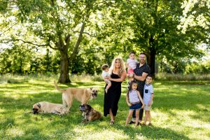 A photo of Danny Gokey, his family and his dogs in a lush field | Celebrity Dogs and Their People by Sara Kauss